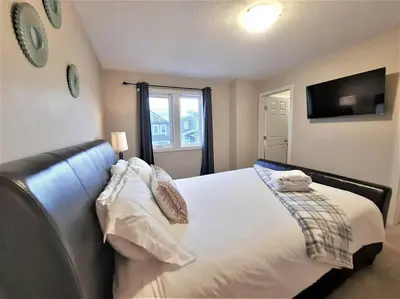 a bedroom with a large bed and a television at Stylish Getaway by Spruce Meadows in Calgary