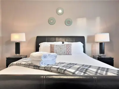 a bedroom with a bed with two lamps and two towels at Stylish Getaway by Spruce Meadows in Calgary