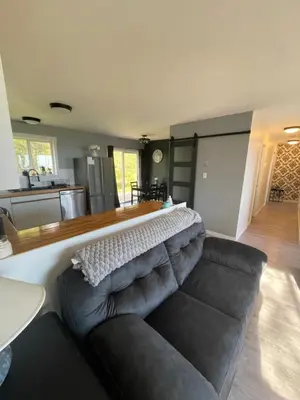 a living room with a couch and a kitchen at Sunrise Mountain view Skidegate House in Skidegate
