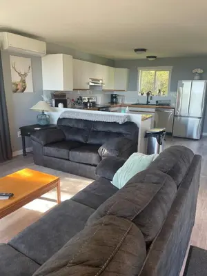 a living room with a couch and a kitchen at Sunrise Mountain view Skidegate House in Skidegate