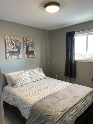 a bed in a bedroom with two paintings on the wall at Sunrise Mountain view Skidegate House in Skidegate