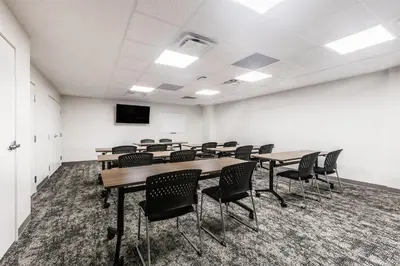 a conference room with tables and chairs and a screen at Staybridge Suites - Dawson Creek by IHG in Dawson Creek