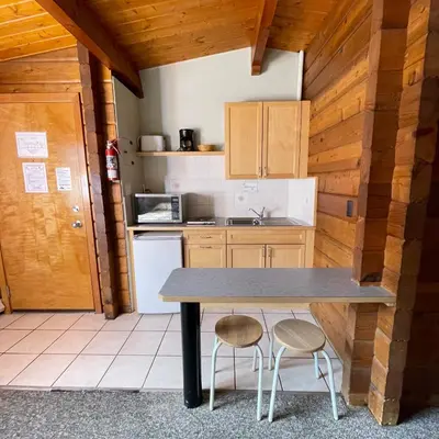 a kitchen with a table and two stools at Raccoon Lodge Motel in Sylvan Lake