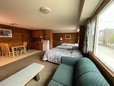 a bedroom with a bed and a couch and a table at Raccoon Lodge Motel in Sylvan Lake