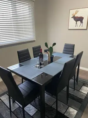 a table with chairs and a bottle of wine on it at Wonderful 2-bedroom apartment in Camrose