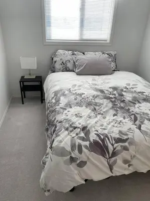 a bedroom with a bed with a flowery blanket and a window at Cozy Home in Camrose