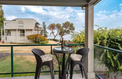 a patio with a table and chairs on a balcony at Sunrise Cove Apt at Inn of The Sea in Ladysmith