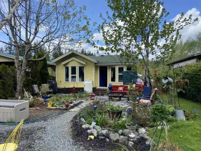 a garden in front of a yellow house at Beaver Lake Resort Site #36 in Lake Cowichan
