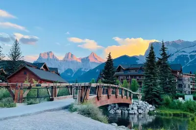 a bridge over a river with mountains in the background at unit #301 Mountain view 2BR in Canmore Down town in Canmore