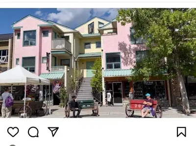 two people sitting on benches in front of a building at unit #301 Mountain view 2BR in Canmore Down town in Canmore