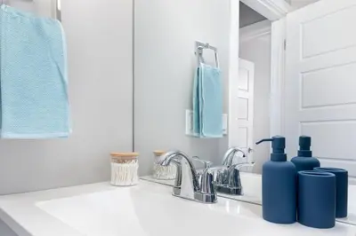 a white kitchen with blue bottles on a sink at Modern & Stylish 1-Bedroom Unit in Edmonton