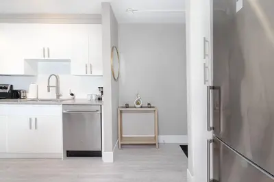 a white kitchen with a sink and a refrigerator at Modern & Stylish 1-Bedroom Unit in Edmonton
