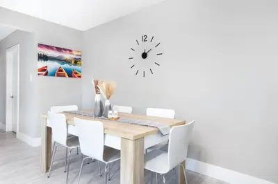 a dining room with a wooden table and white chairs at Modern & Stylish 2-Bedroom Unit in Edmonton