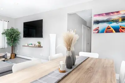 a dining room with a wooden table and white chairs at Modern & Stylish 2-Bedroom Unit in Edmonton
