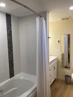 a bathroom with a tub and a shower curtain at Bright poolside walkout two bedroom basement suite in the Okanagan in Penticton