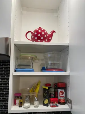 a cupboard filled with lots of dishes and a tea pot at Bright poolside walkout two bedroom basement suite in the Okanagan in Penticton