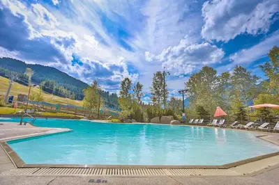 a large swimming pool with chairs and a mountain at Hearthstone Townhomes by StayIn in Panorama
