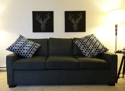 a couch in a living room with two pillows on it at Mountain Retreat - Modern and Bright with Panorama Views 2 bedrooms, 4 beds, heated all-year outdoor pool, hottub, balcony, Banff Park Pass in Canmore