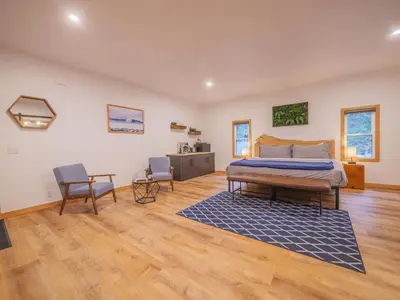 a bedroom with a bed and two chairs in it at Winter's Hideaway Suite in Ucluelet