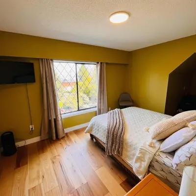 a bedroom with a bed and a large window at Oceanside Manor - Ocean View in Qualicum Beach