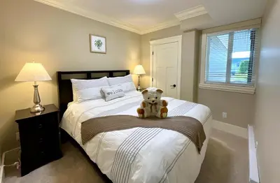 a teddy bear sitting on a bed in a bedroom at New two-bedroom legal suite with parking in White Rock