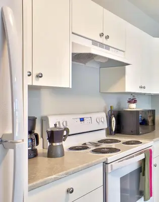 a kitchen with white cabinets and a stove top oven at Zen Retreat Langford in Victoria