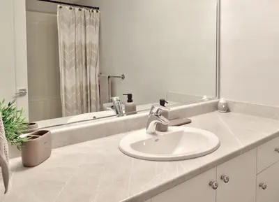 a white bathroom with a sink and a mirror at Zen Retreat Langford in Victoria