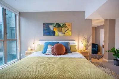 a bedroom with a large bed with a large window at Heart of Downtown King Suite/Parkng/Pool/Gym/Sauna in Vancouver