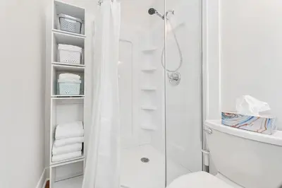 a white bathroom with a shower and a toilet at The Beach House Suite by EMR Vacation Rentals in Chemainus