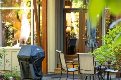 a patio with two chairs and a table with a trash can at Pacific Forest Beach House in Parksville