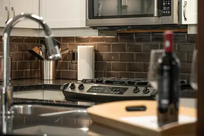 a kitchen counter with a stove and a sink at Pacific Forest Beach House in Parksville