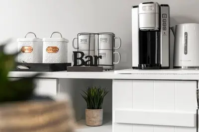 a counter with three mugs and a coffee maker on it at Cozy Home - 9mins to WEM -Foosball -Vintage arcade - Air conditioning in Edmonton