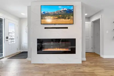 a living room with a fireplace with a tv above it at Cozy Home - 9mins to WEM -Foosball -Vintage arcade - Air conditioning in Edmonton