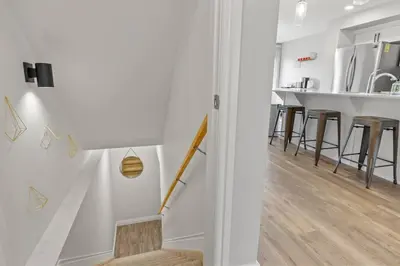 a living room with white walls and wooden floors and a staircase at Cozy Home - 9mins to WEM -Foosball -Vintage arcade - Air conditioning in Edmonton