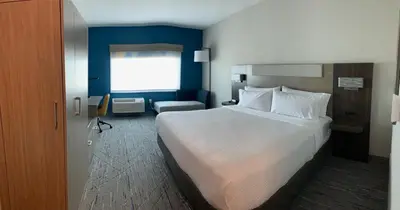 a hotel room with a large bed and a chair at Holiday Inn Express & Suites Courtenay - Comox by IHG in Courtenay