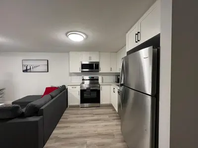 a kitchen with a couch and a stainless steel refrigerator at Cozy New Suite in NW Calgary in Calgary