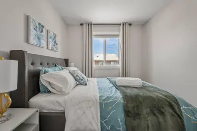 a bedroom with a large bed and a window at Stylish 3BR Townhouse by Airport in Calgary