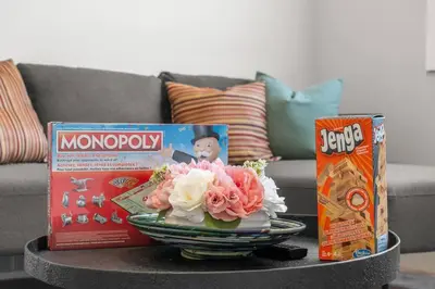 a table with a bowl of flowers and a box of monopoly at Stylish 3BR Townhouse by Airport in Calgary
