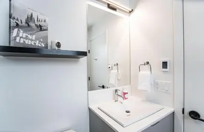 a white bathroom with a sink and a mirror at Switchback Suite by Revelstoke Vacations in Revelstoke