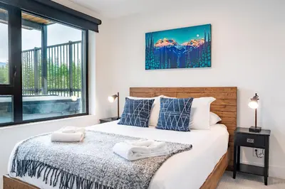 a bedroom with a bed and a large window at Switchback Suite by Revelstoke Vacations in Revelstoke