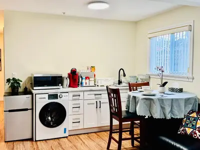 a kitchen with a washing machine and a table at Cozy 2 beds Spacious rooms,Close to transit in Vancouver