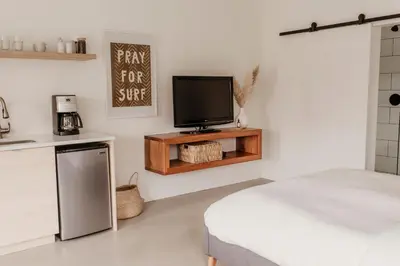 a room with a tv and a bed and a kitchen at Drift West Coast Getaway in Ucluelet