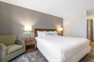 a bedroom with a large white bed and a chair at Home Inn and Suites Lloydminster in Lloydminster