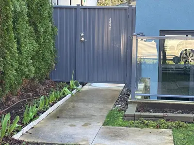 a driveway in front of a building with a fence at Fancy Family Suite with Parking near UBC in Vancouver