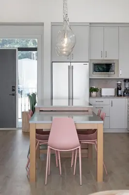 a kitchen with a table and pink chairs at Beachfront Luxury Suite #18 at THE BEACH HOUSE in Campbell River