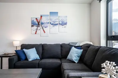a living room with a black couch and some mountains at Alpine Dream by Revelstoke Vacations in Revelstoke