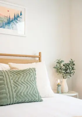 a bed with a green pillow and a picture on the wall at Adanac by Revelstoke Vacations in Revelstoke