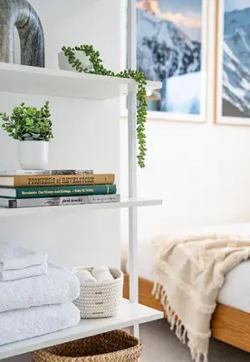 a white shelf with towels and books in a bedroom at Adanac by Revelstoke Vacations in Revelstoke