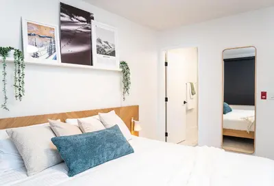 a white bedroom with a bed and a mirror at Adanac by Revelstoke Vacations in Revelstoke