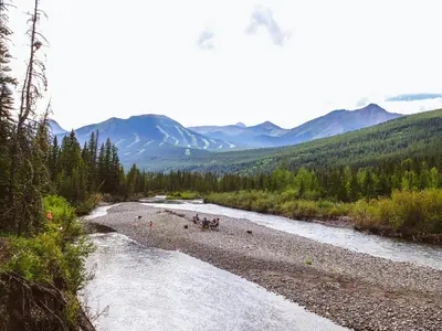 a river with a group of people on the shore at Sundance By Basecamp in Kananaskis Village